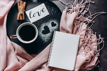 Valentines day background. Cup of coffee, notebook,  scarf, cinnamon and heart on gray table. Valentines and Mother's Day concept. Flat lay, top view, copy space