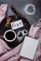 Naklejka premium Valentines day background. Cup of coffee, notebook, scarf, cinnamon and heart on gray table. Valentines and Mother's Day concept. Flat lay, top view, copy space
