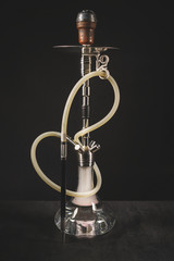Modern transparent hookah on black background. Hookah with rubber tube and flask. Eastern water pipe smoking 
