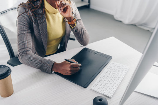 partial view of african american designer using graphic tablet at desk in modern office