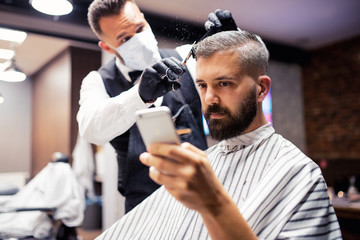 Hipster man client visiting haidresser and hairstylist in barber shop, taking selfie.