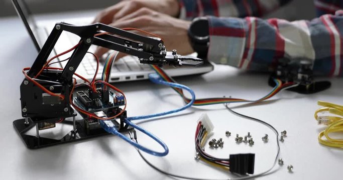 robotics engineer programming robot arm for automation project