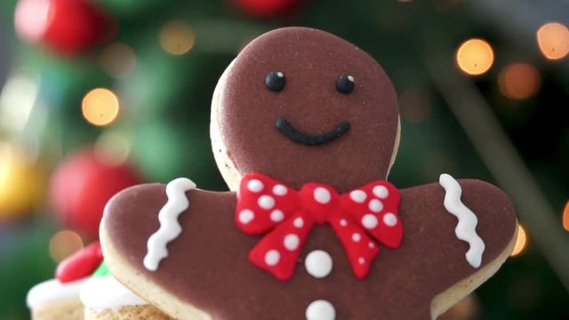 Close up of Gingerbread Man cookie in front of a Christmas Tree