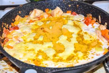 cooking yellow curry in a saucepan skillet many spices spicy chicken