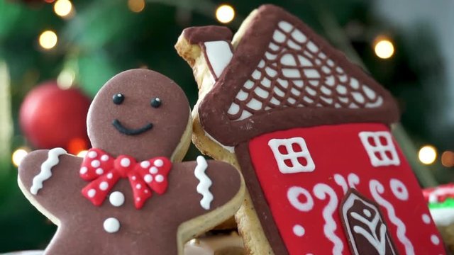 Gingerbread Man and Gingerbread House cookies in front of a Christmas Tree