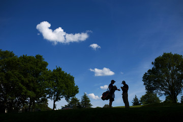 Golfer and caddy discussing tactics on a sunny day