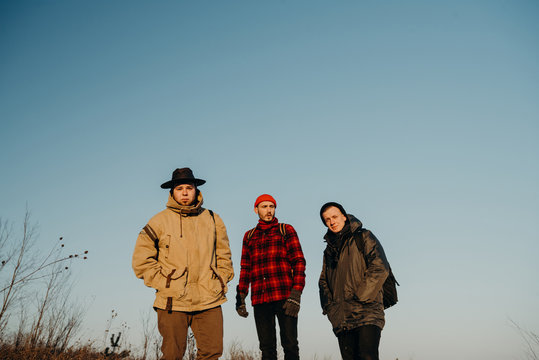 Three friends stand on a hill during a beautiful sunset. Winter trip. Relax and meeting friends. Friendship and longevity. 