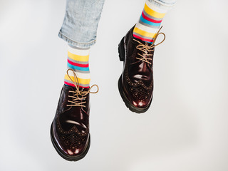 Men's legs in bright, striped, multi-colored socks and stylish, vintage shoes on a white, isolated...