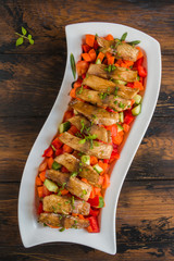 Tilapia fish fillet roasted in olive oil and served with fresh vegetable salad in white dish on wooden rustic table, top view