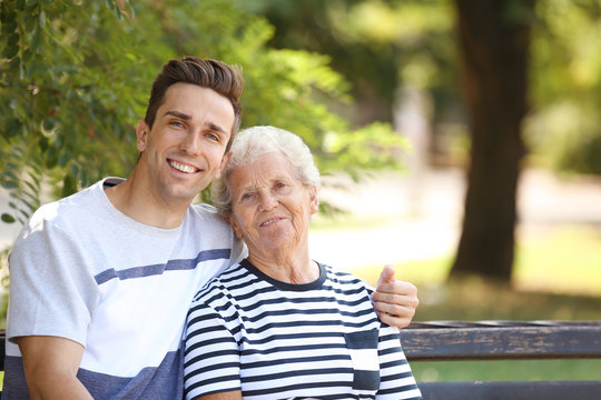 Man with elderly mother on bench in park
