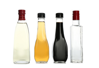 Glass bottles with different kinds of vinegar on white background