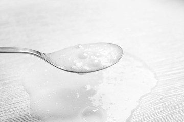 Chemical reaction of vinegar and baking soda in spoon over white wooden table