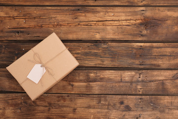 Parcel with tag and space for text on wooden background, top view