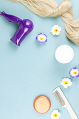 Hairdressing tools, nourishing mask and hair extensions on blue wooden background. Hair care concept flat lay. Top view