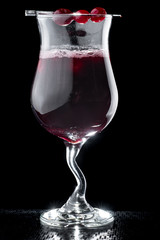 beautiful burgundy cocktail with ice garnished with an orange slice in a Hurricane glass isolated on a black background. close up. dark background