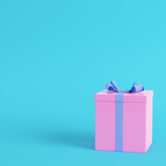 Pink gift box with ribbon bow on bright blue background in pastel colors