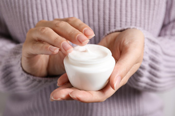Fototapeta na wymiar Woman holding jar of moisturizing cream, closeup. Winter skin care cosmetic