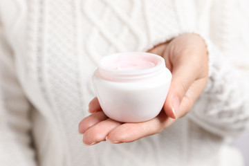 Obraz na płótnie Canvas Woman holding jar of moisturizing cream, closeup. Winter skin care cosmetic