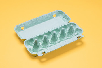 Empty egg carton on yellow.  Dozen egg crate container empty on a bright pastel yellow background