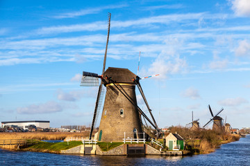 Naklejka premium Old, traditional windmill in the Dutch canals. Netherlands.White clouds on a blue sky, the wind is blowing.