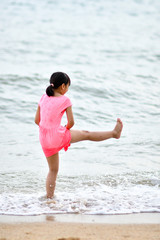 Fototapeta na wymiar Asian girl with pink dress playing by the seaside