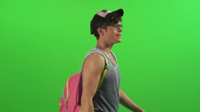 Young hipster looking backwards while walking sideways happily.