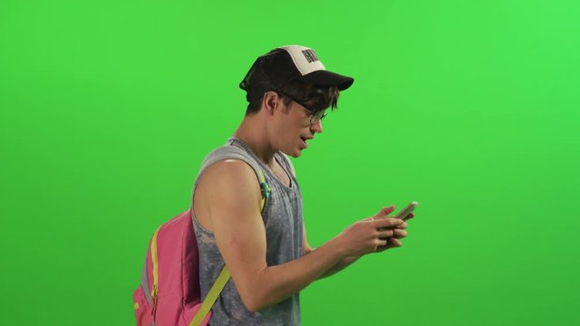 Young hipster texting and laughing while walking.