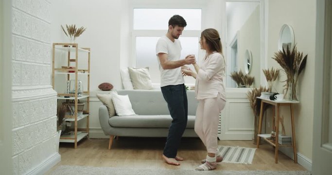 Home style couple spending a wonderfully time together in the living room dacing together , in pajamas.