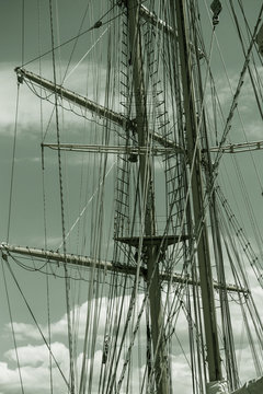 Close-up of a mast on traditional sailboats. The mast of large wooden ship. Beautiful travel picture with masts and rigging of sailing ship against blue orange sky. Background for tourist advertising