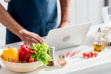 Obraz na płótnie Canvas partial view of man working on laptop on white kitchen table