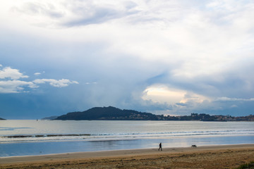 Man walking on the beach on a cloudy day