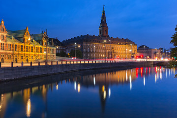 The Old Stock Exchange Boersen and Christiansborg Palace with their mirror reflection in canal at night, Copenhagen, capital of Denmark