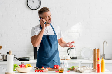  adult man speaking on smartphone at kitchen