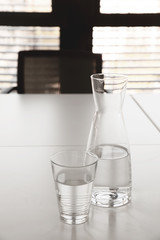 Glaskaraffe mit Wasser und Glas auf Bürotisch