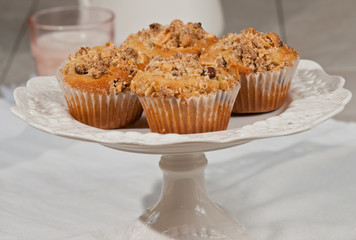 Top view, medium distance of five strawberry buttermilk muffins, freshly baked, homemade, in paper form on a pedestal dish  on white table cloth