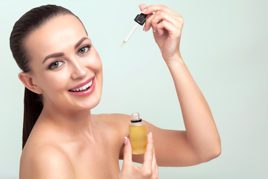 Closeup shot of cosmetic oil applying on young woman's face with pipette. Beauty therapy concept.