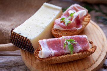 Serrano ham and manchego cheese tapas on rustic wooden table.