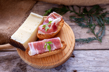 Serrano ham and manchego cheese tapas on rustic wooden table.