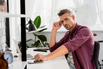  man sitting at table with laptop and smartphone at home office