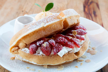 Close up of vanilla ice cream with waffle and fresh strawberry on wood table background