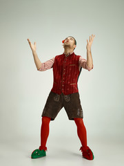 The happy smiling friendly man dressed like a funny gnome or elf pointing up on an isolated gray...
