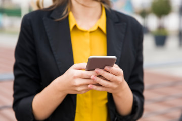 Executive working with a mobile phone in the street with office buildings in the background