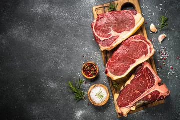 Photo sur Plexiglas Viande Steak de boeuf de viande crue sur la vue de dessus noire.