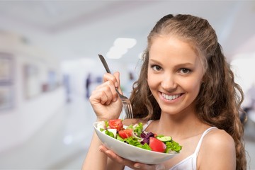 Young woman with bowl of salad on healthy food background