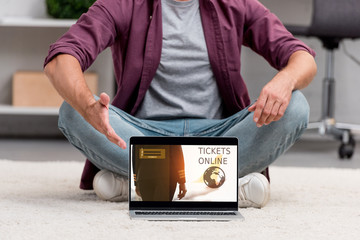 cropped view of man pointing at laptop with tickets online illustration