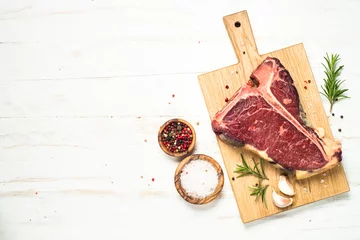 Foto op Plexiglas Steakhouse T-bone biefstuk op wit met kruiden.