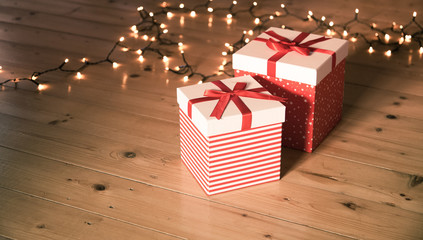 red gift boxes and christmas lights on wooden floor