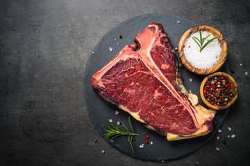 T-bone beef steak on black with spices.