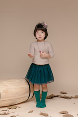 Little pretty Asian girl sitting in an autumn background.