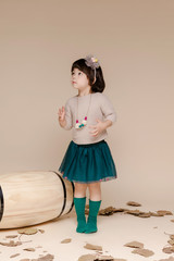 Little pretty Asian girl sitting in an autumn background.